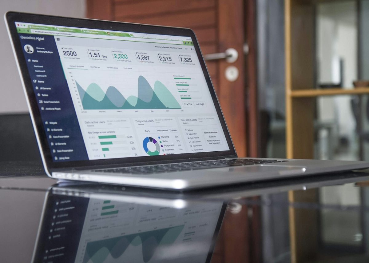 A laptop showing revenue charts and figures on a desk