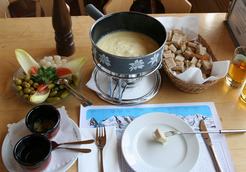 A Swiss cheese fondue in a caquelon pot with bread and white wine