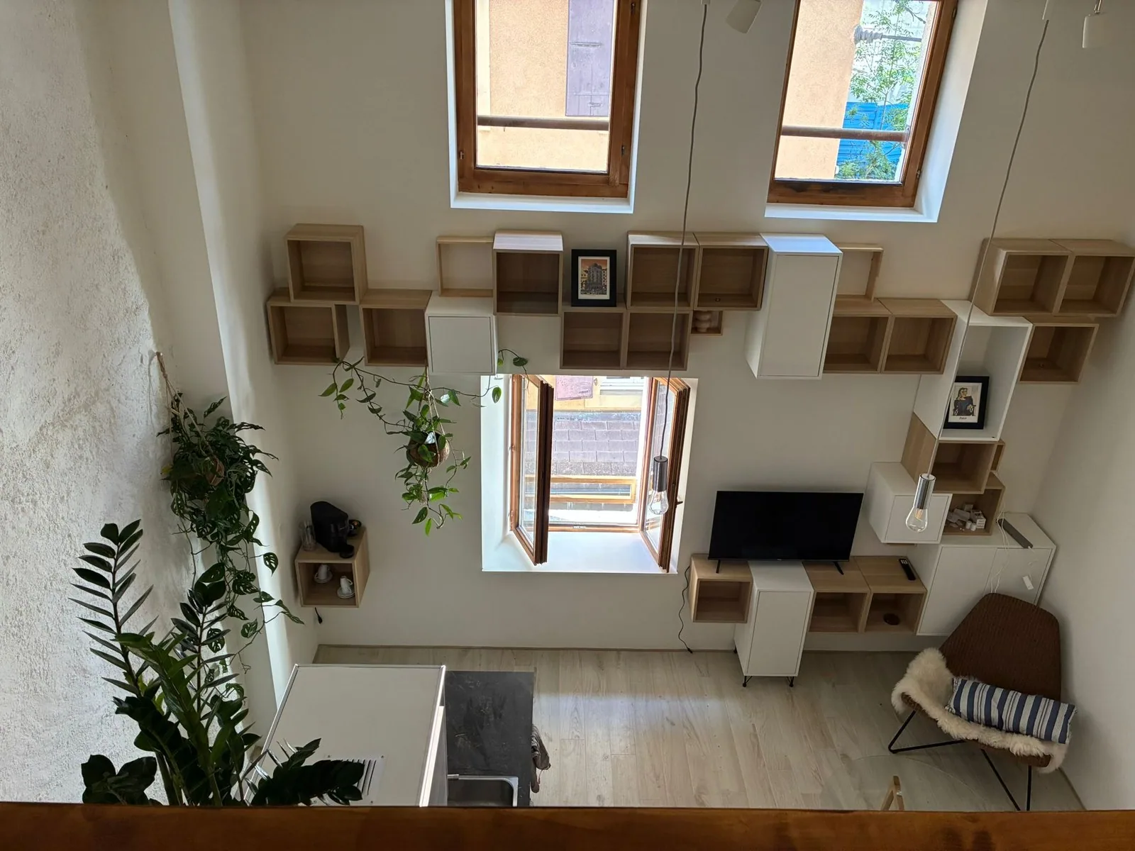 Séjour vu depuis la mezzanine — mur de bibliothèques, télévision et fauteuil