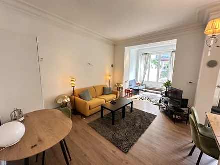 Séjour vu depuis la salle à manger, avec le canapé et la télévision